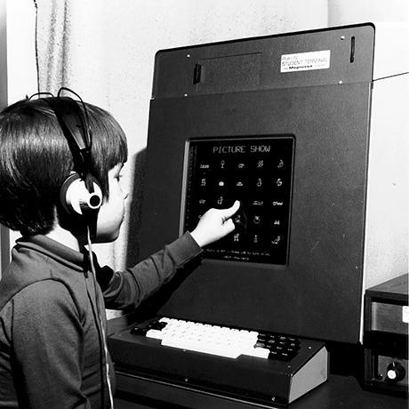 child wearing headphones touching a video display