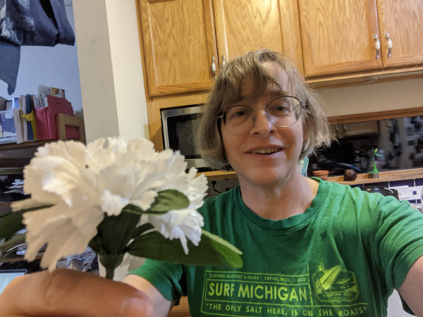 person holding flower but looking at you