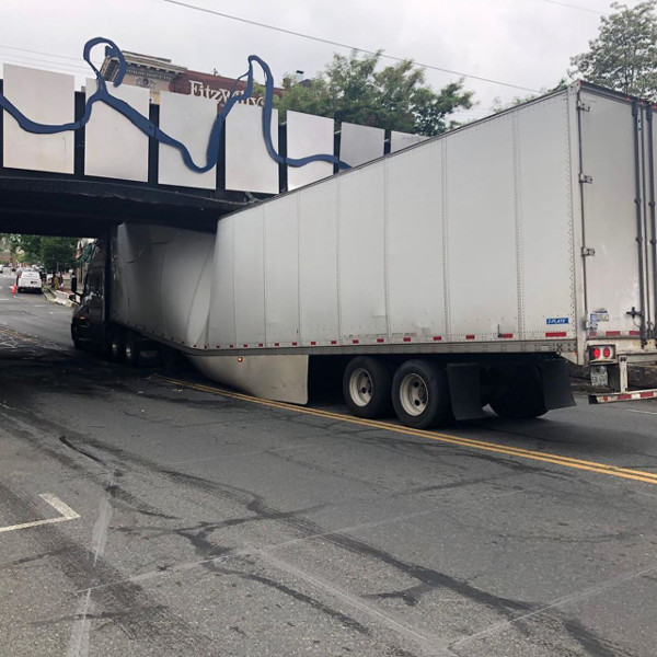 a truck stuck under a low bridge