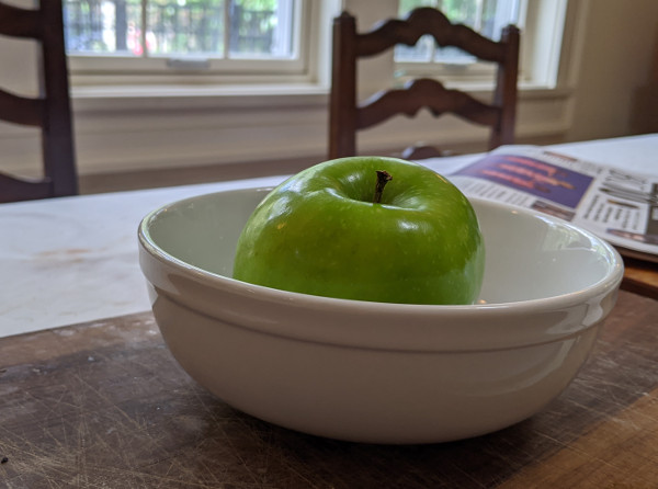 apple sitting in bowl, only the top of apple visible