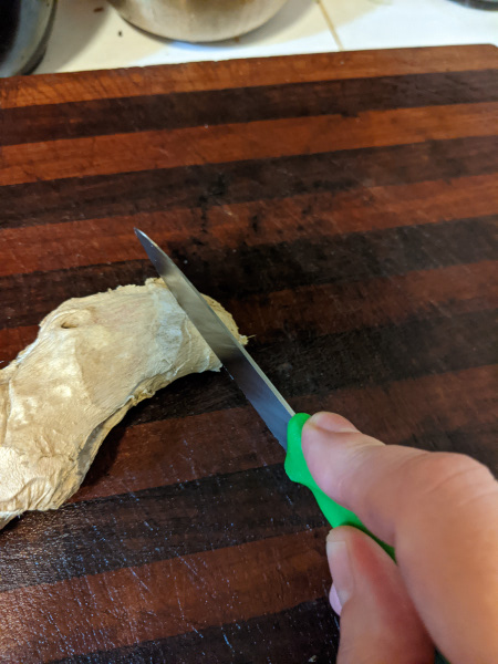 knife cutting a piece of ginger